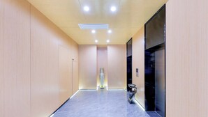 A modern hallway with a marble floor, wooden panel walls, and a central decorative vase. - Sanya Coconut Dream Corri RenJoy Hotel (Sanya)