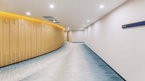A modern hotel corridor with a curved wooden wall on the left, a blue carpet, and a sign with a phone number on the right. - Sanya Coconut Dream Corri RenJoy Hotel (Sanya)