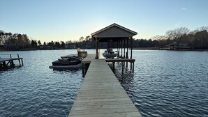 A wooden dock extending into calm water, with a covered pavilion at the end. - Sinclair Sunsets - Sleeps 6, Waterfront, Fire pit, Kayaks, Games + MORE! (Eatonton)