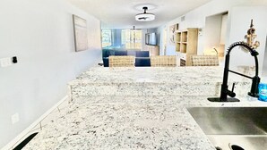 Una cocina amplia con encimera de granito, un grifo moderno y vistas al salón.