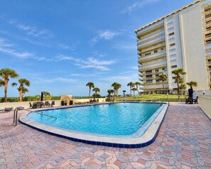 Piscina com borda azulejada, rodeada por um pátio de tijolos.