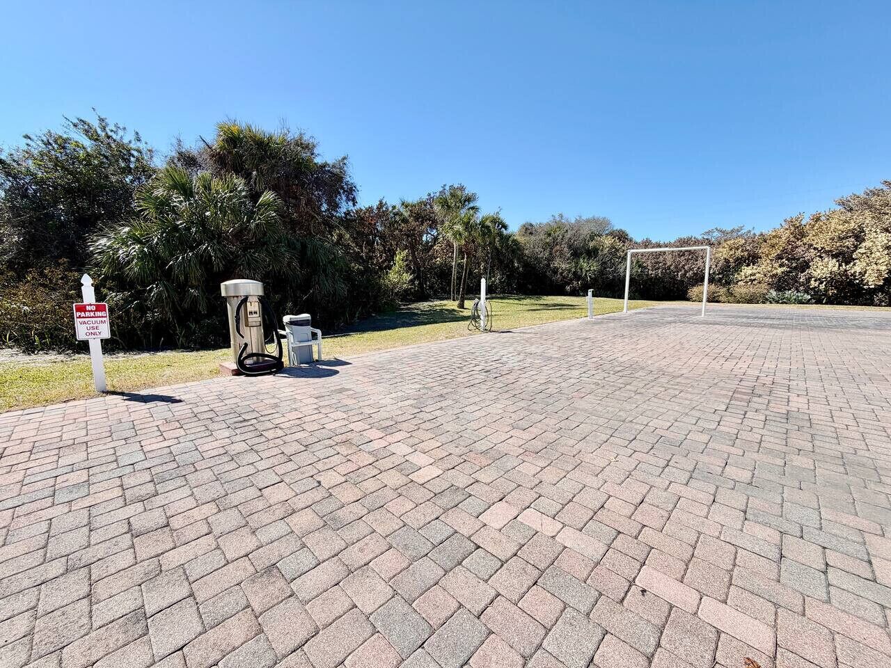 A paved area with a sign indicating no parking, a bicycle, and a fuel pump.