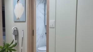 Kylpyhuone, jossa on wc, käsienkuivaaja, hiustenkuivaaja ja taulu seinällä.