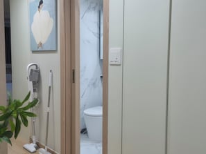 Ein Badezimmer mit Toilette, einem Handtrockner, einem Fön und einem Bild an der Wand.