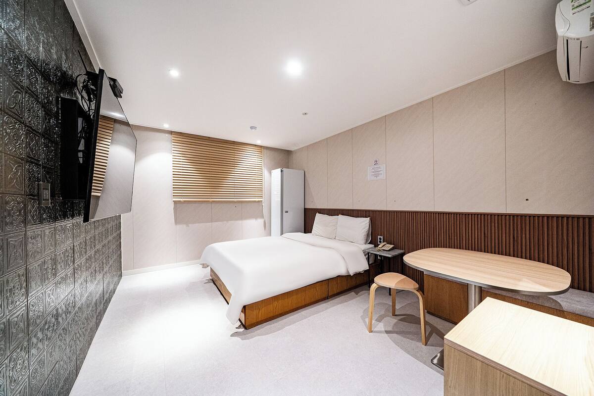 Una camera d'albergo moderna con un letto, un comodino, una sedia e una piccola scrivania.