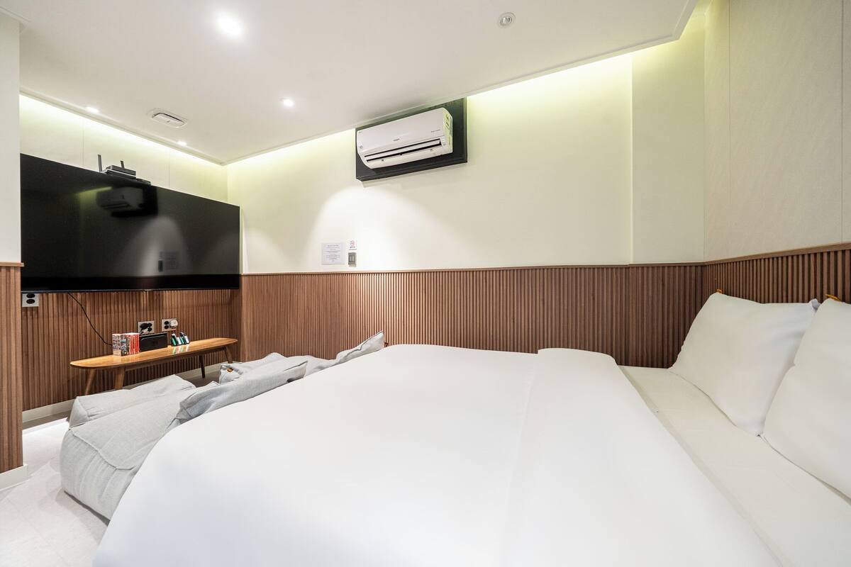 Una camera d'albergo con un letto, un comodino e un condizionatore d'aria a parete.