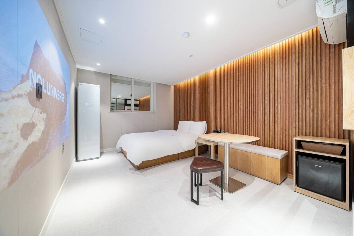 Camera d'albergo moderna con un letto, una scrivania, una sedia, una televisione e un pannello decorativo in legno.