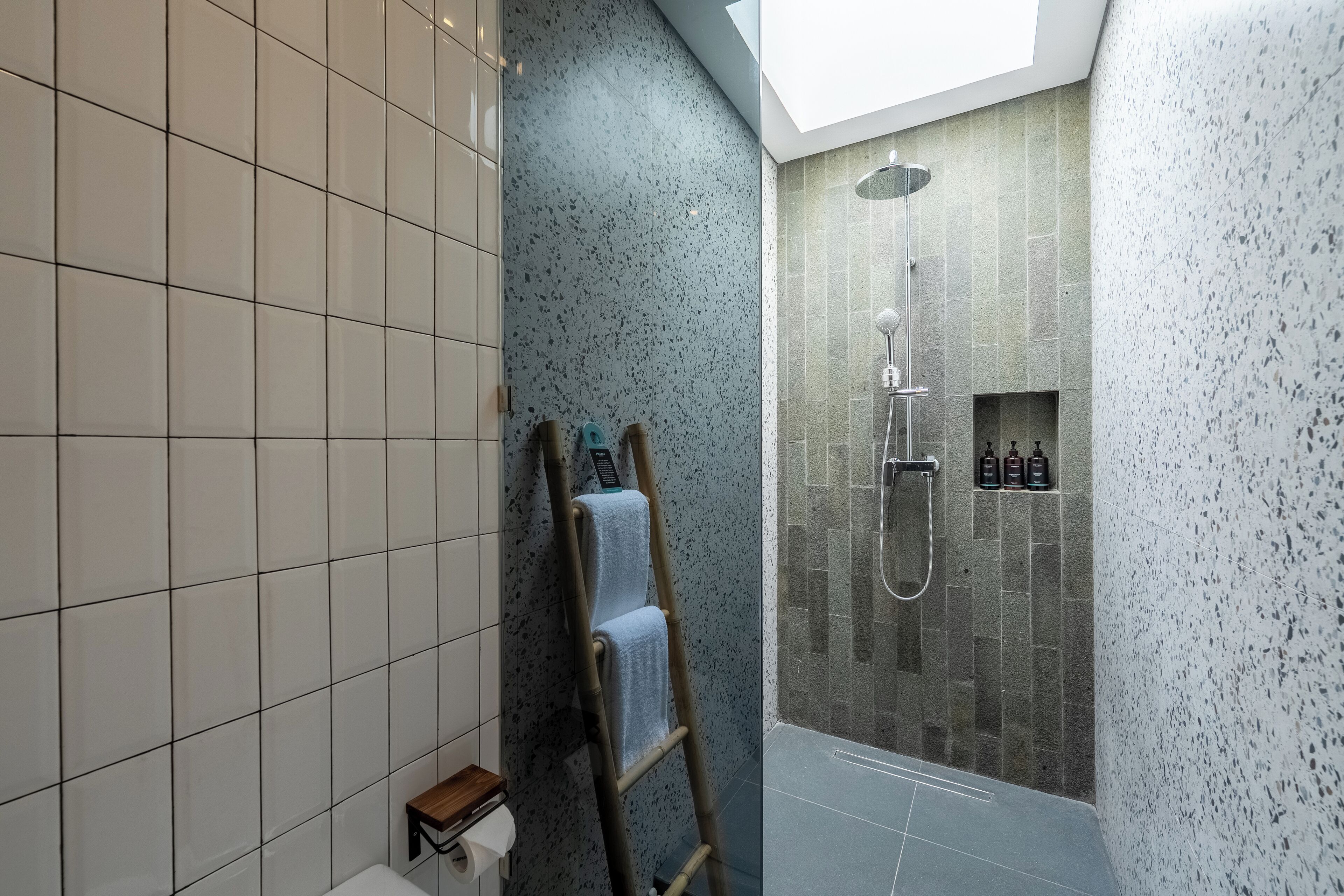 A modern bathroom with a skylight, a shower with a rain showerhead, and a towel rack.