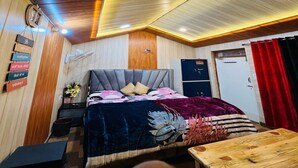 A bedroom with a bed, bedside table, and a wooden ceiling. - The Town Escape Cottage (Dhari)