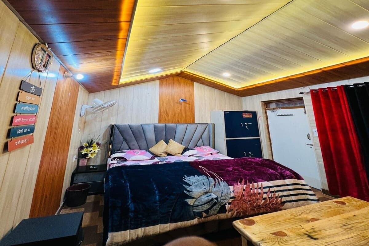 A bedroom with a bed, bedside table, and a wooden ceiling.