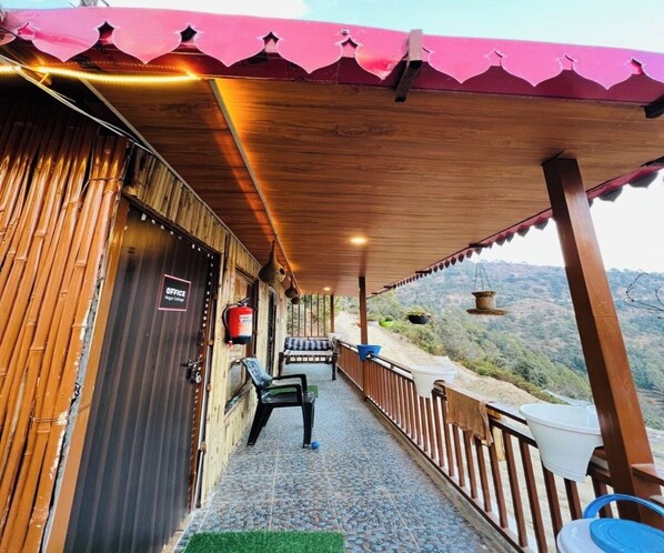 En træbygning med en overdækket veranda, et skilt med teksten "OFFICE" og udsigt til et bakket landskab.