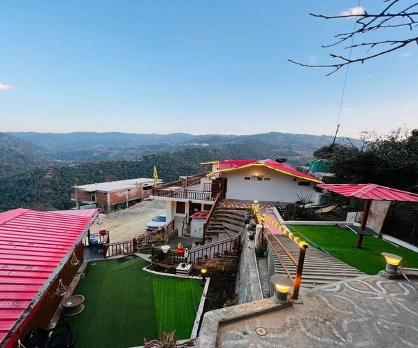 A hotel with multiple buildings, a green lawn, and a scenic mountain view.