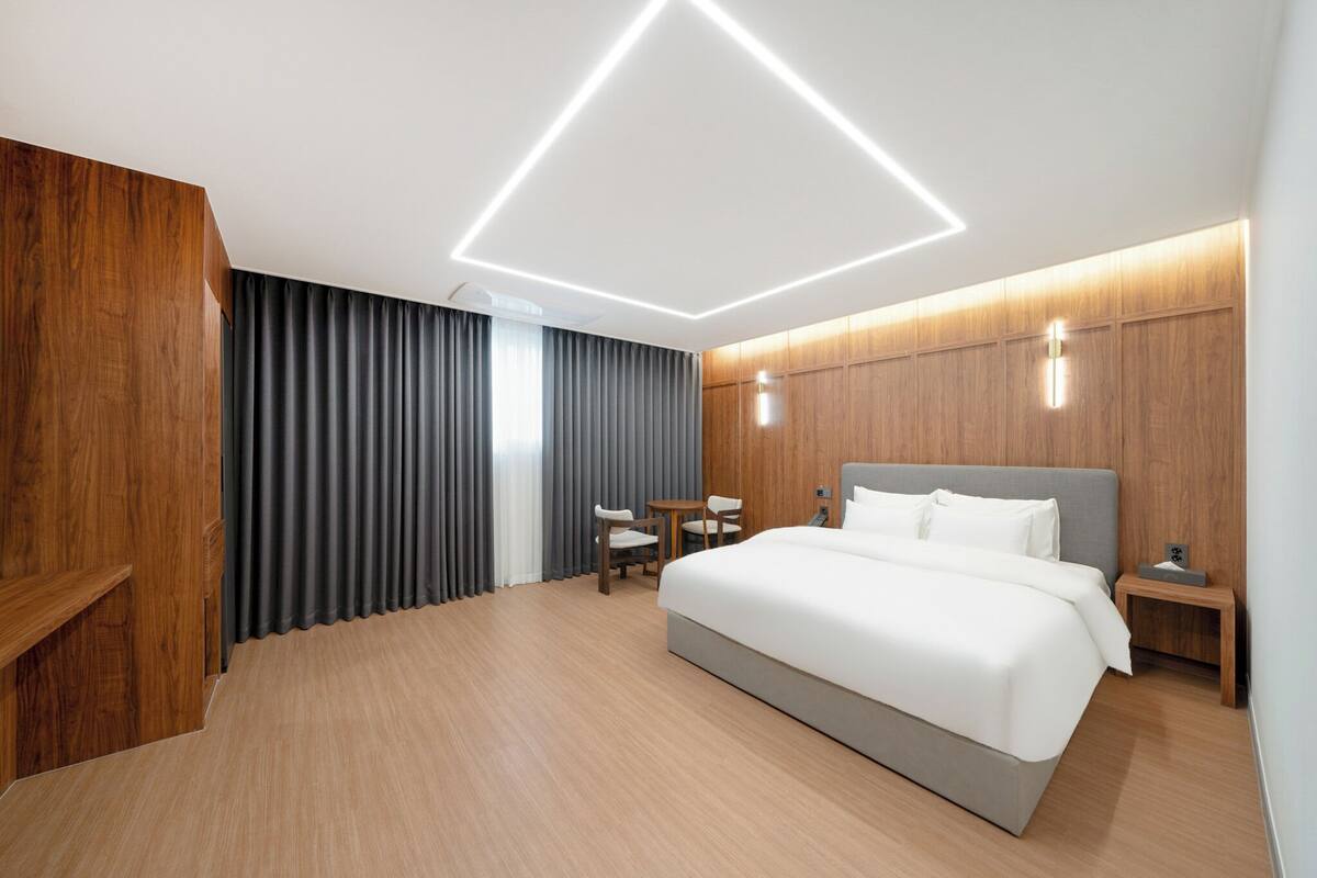 A modern hotel room with a large bed, a desk, and a chair.