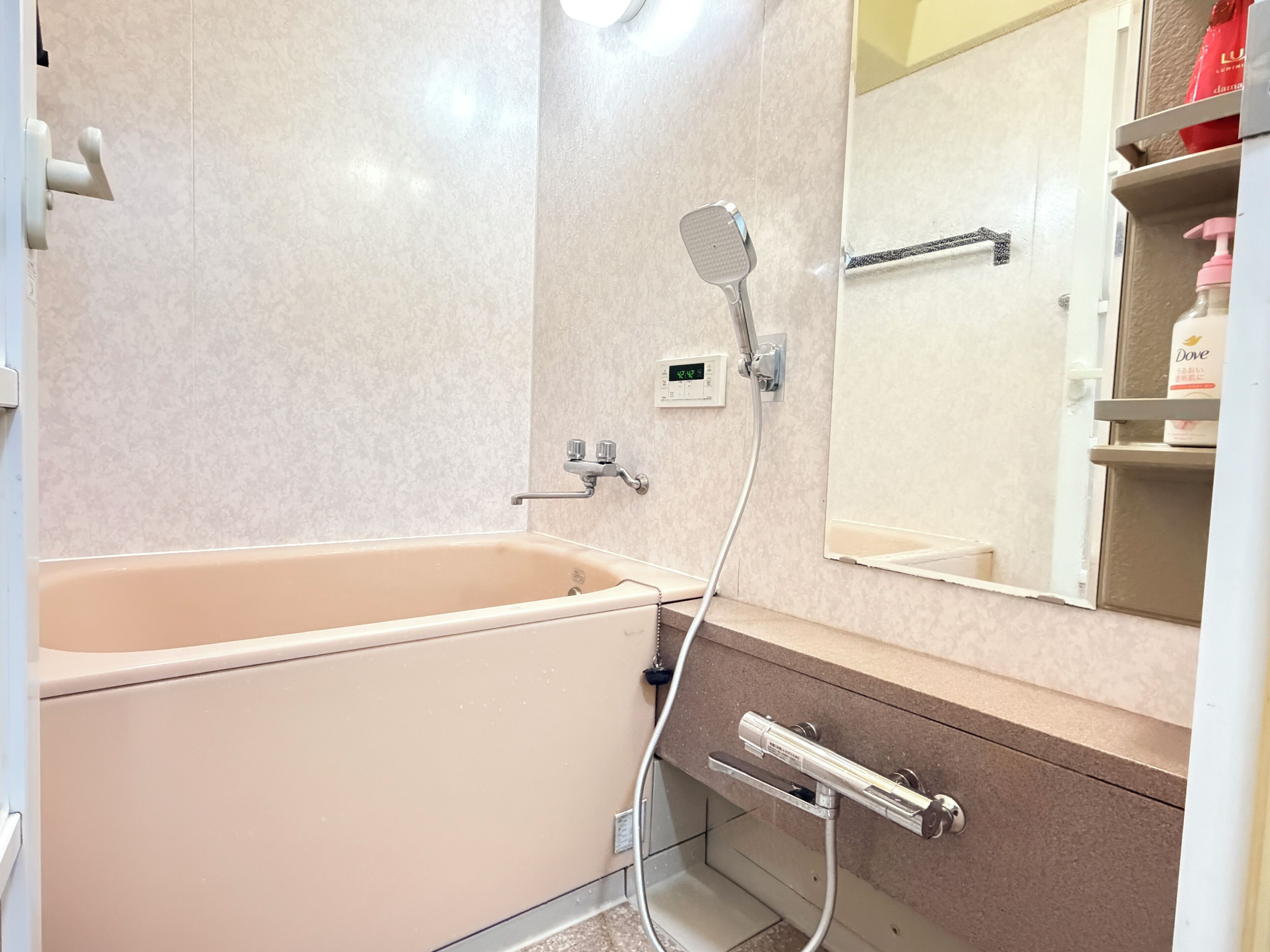 Un baño con bañera, ducha, espejo y toallero.