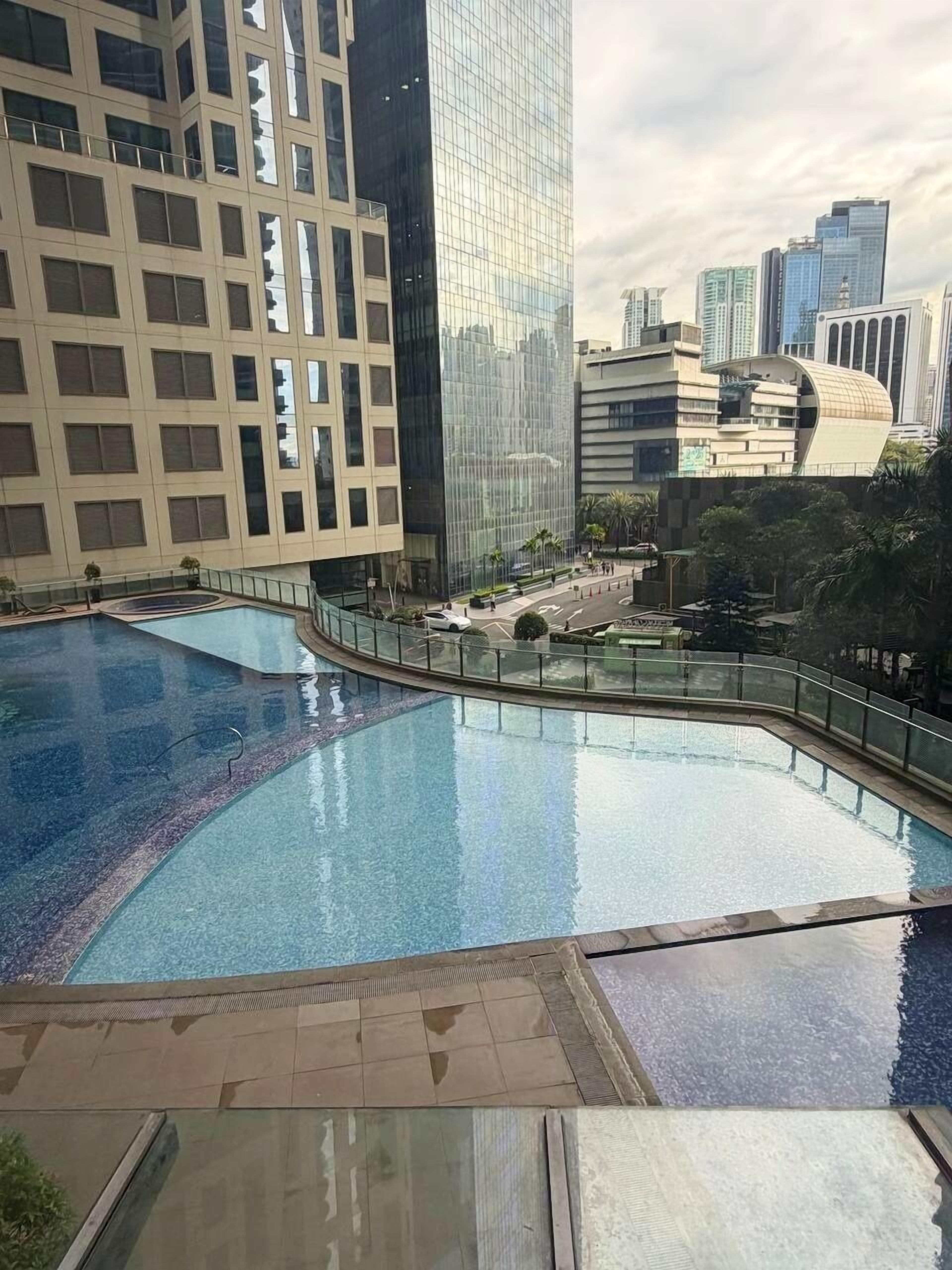 A modern building with a pool area, featuring a glass facade and a curved roof structure.