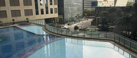 Un edificio moderno con área de piscina, que presenta fachada de vidrio y estructura de techo curva.