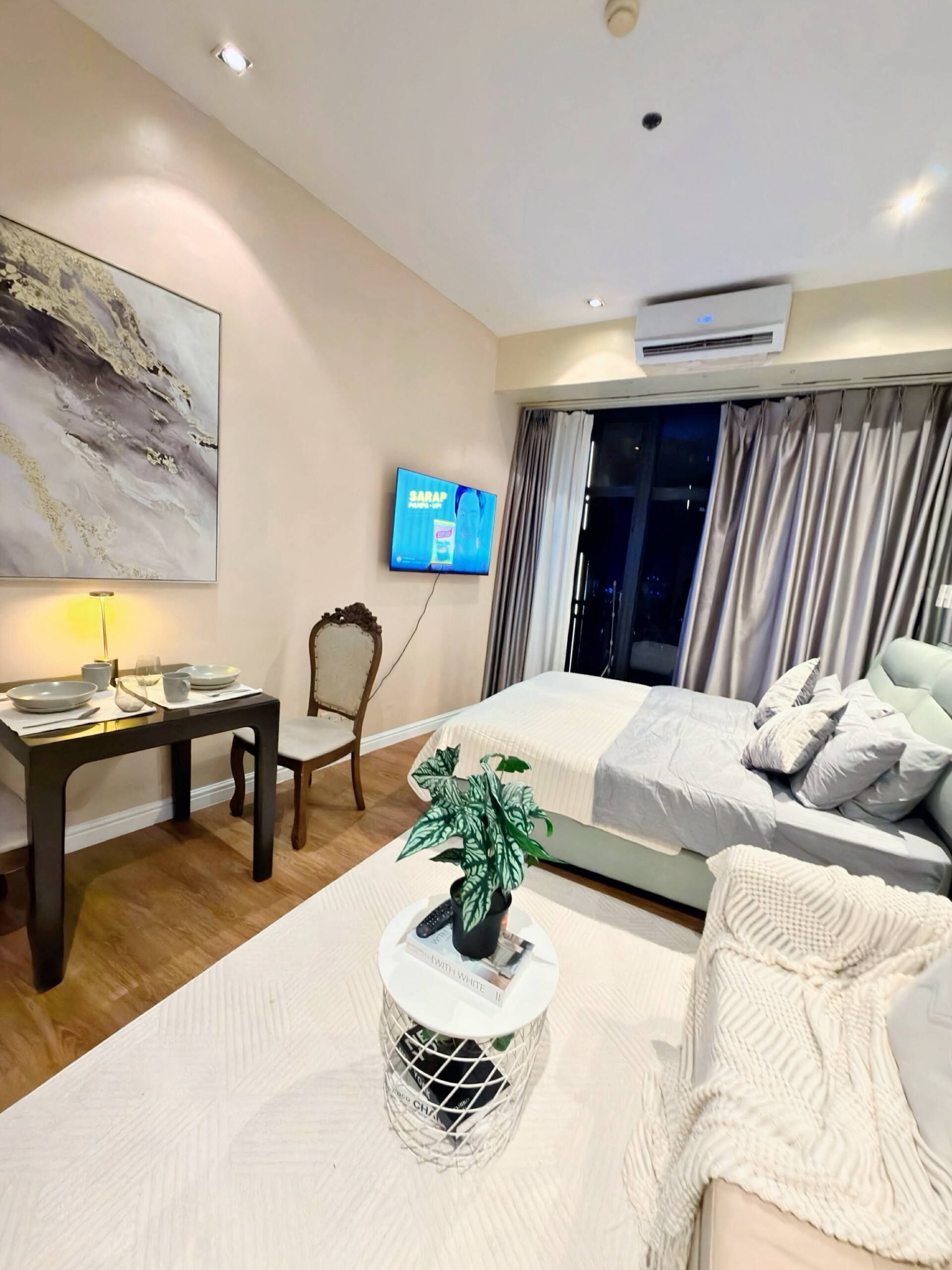 Ein modernes Hotelzimmer mit einem Bett, einem Schreibtisch, einem Fernseher und einer Zimmerpflanze.