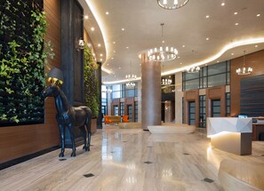 Una hall moderna con una statua di cavallo, una parete verde e una reception.