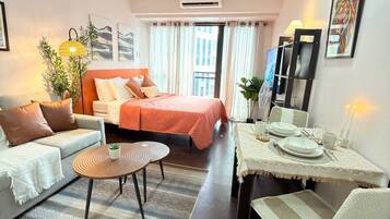 Quarto de hotel moderno com cama, sofá, mesa de jantar e cadeiras.
