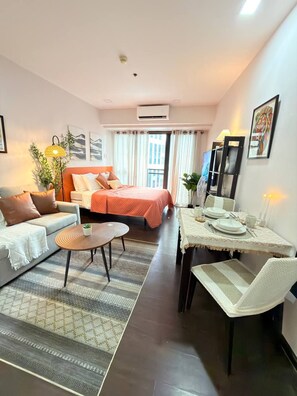 Een moderne hotelkamer met een bed, een bank, een eettafel en stoelen.
