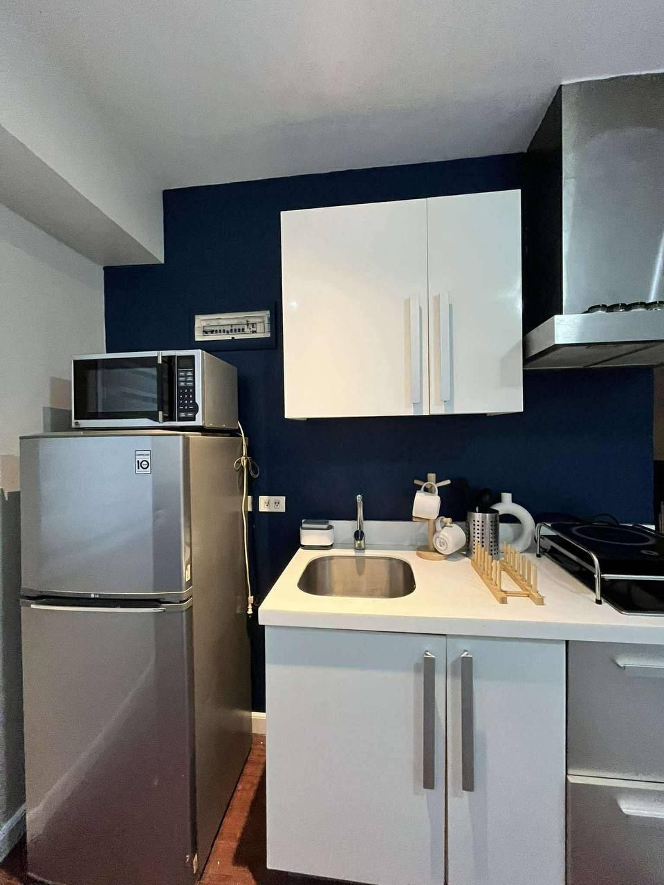 Una cocina compacta con refrigerador de acero inoxidable, microondas, pileta y estufa.