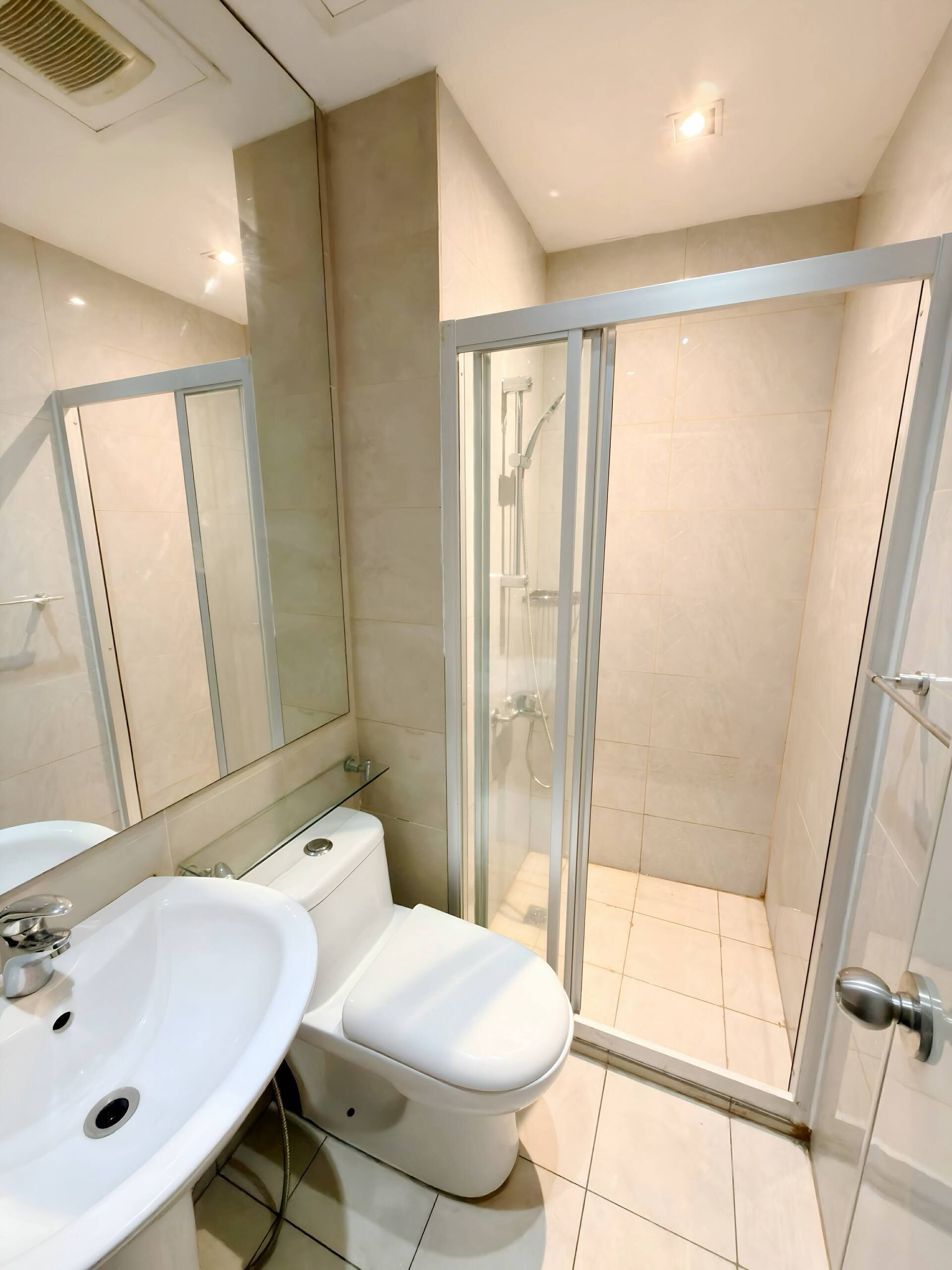 Une salle de bain moderne avec une douche à parois de verre, un lavabo blanc et des toilettes.