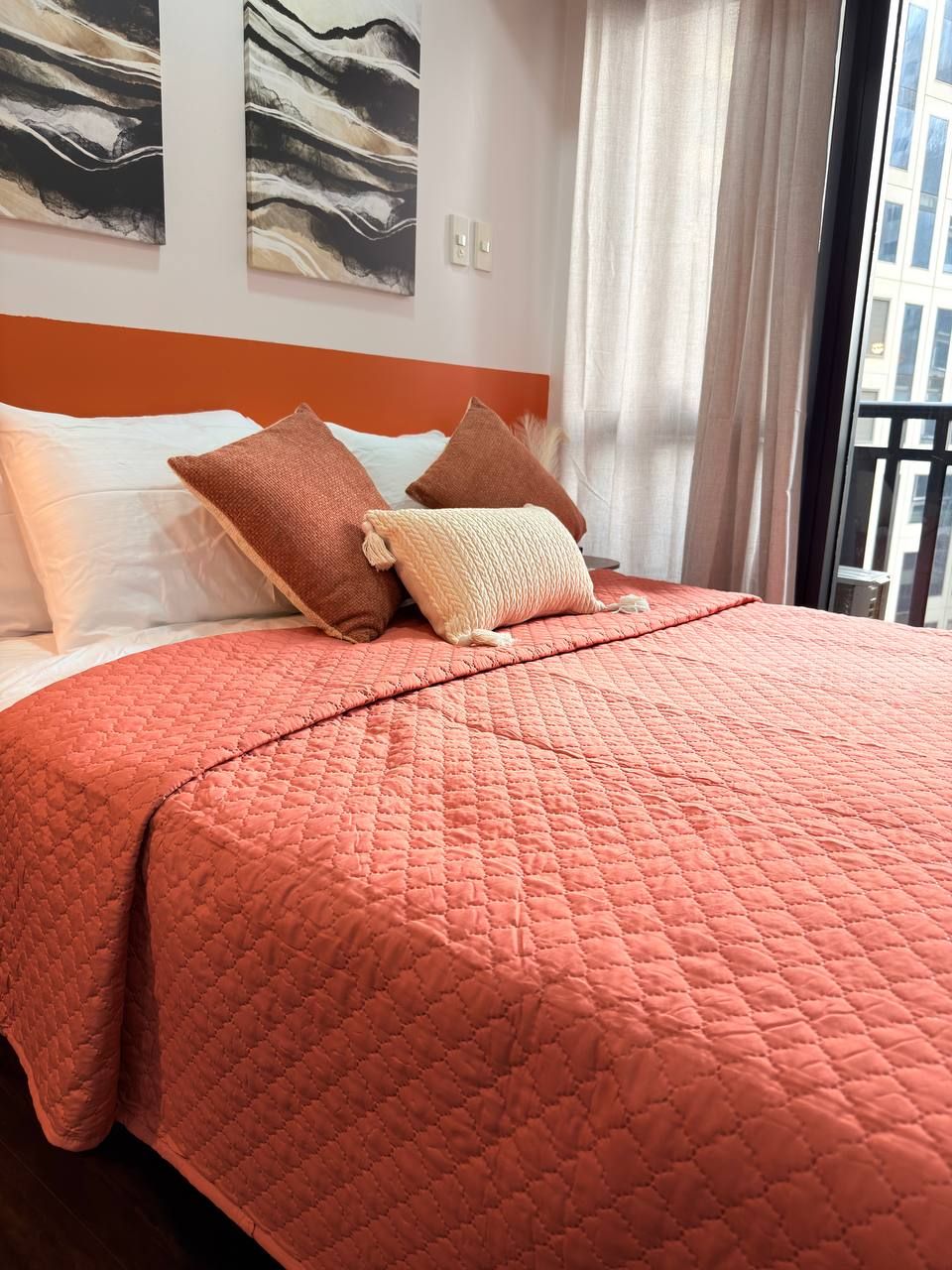 A bed with a pink quilt, white and brown pillows, and a wooden headboard.