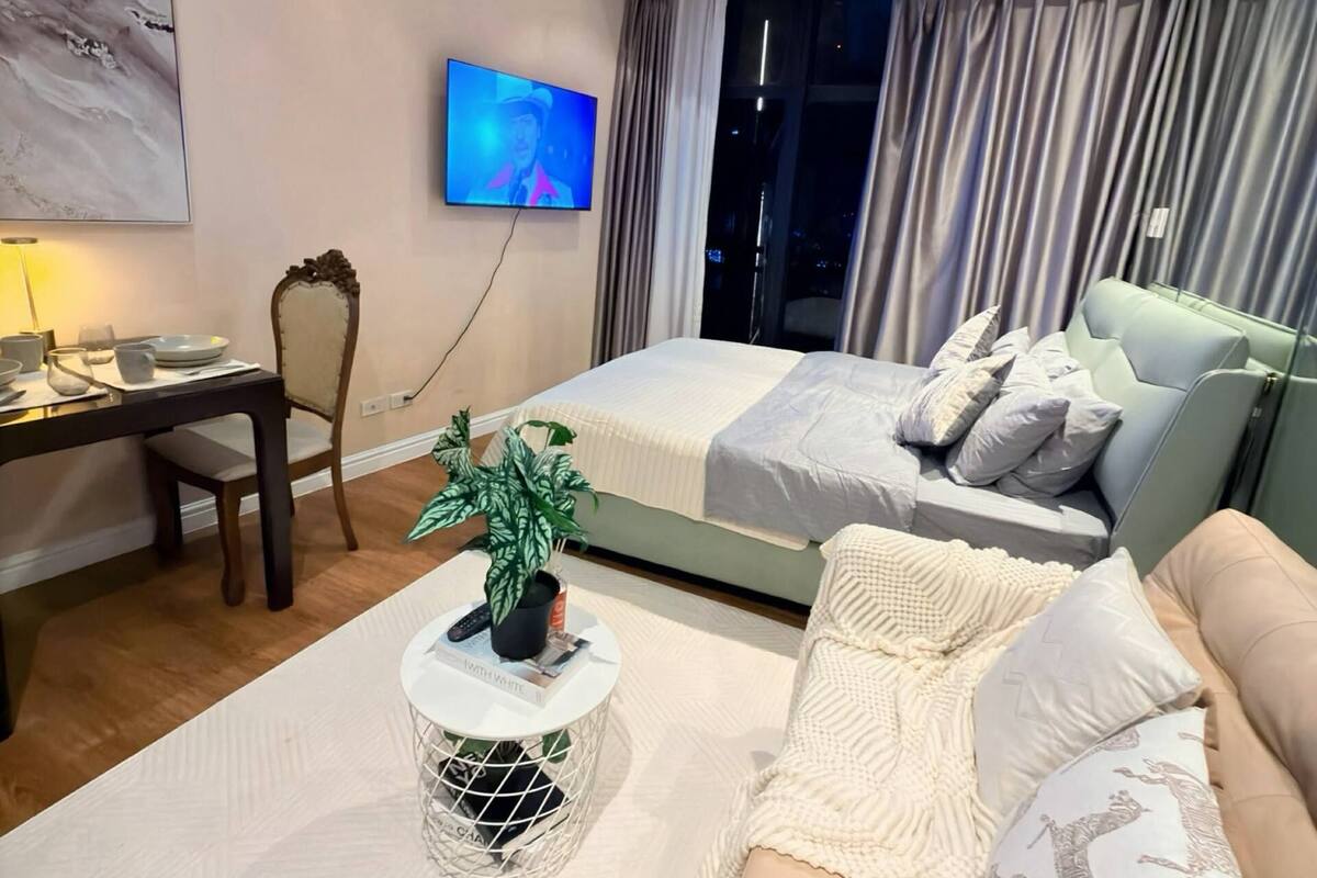 Een moderne hotelkamer met een bed, een slaapbank, een televisie en een bureau.