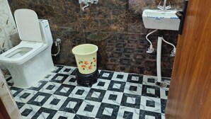 Une salle de bain avec des toilettes, un lavabo et une poubelle.