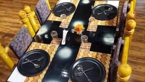 Une table à manger recouverte d’une nappe à carreaux noirs et blancs, avec quatre assiettes noires et des couverts assortis.