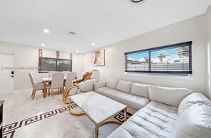 A modern living room with a sofa, coffee table, and dining area.