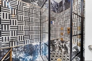 Une salle de bain moderne avec des carreaux aux motifs géométriques et des touches de marbre.