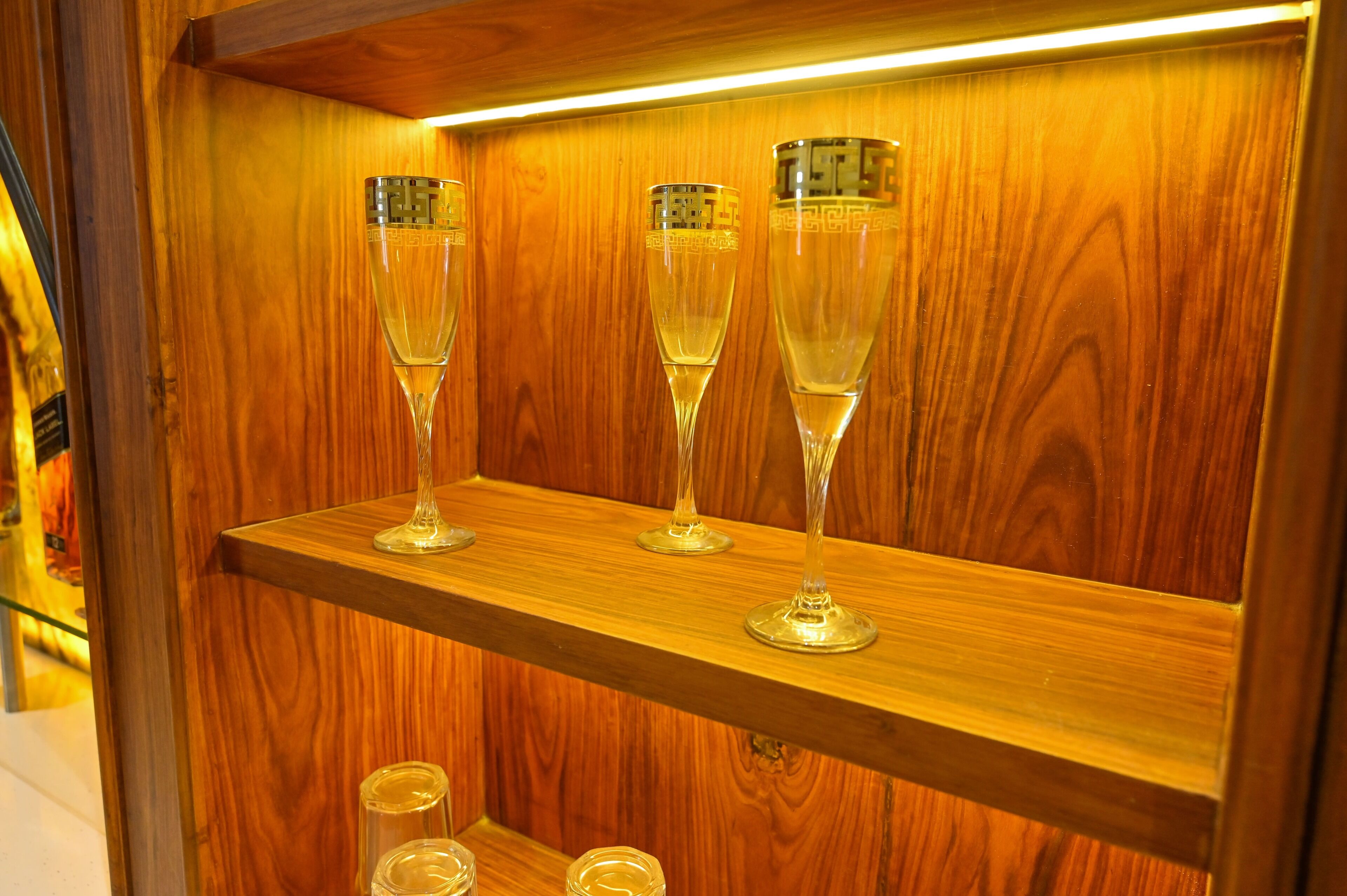 Three champagne flutes on a wooden shelf.