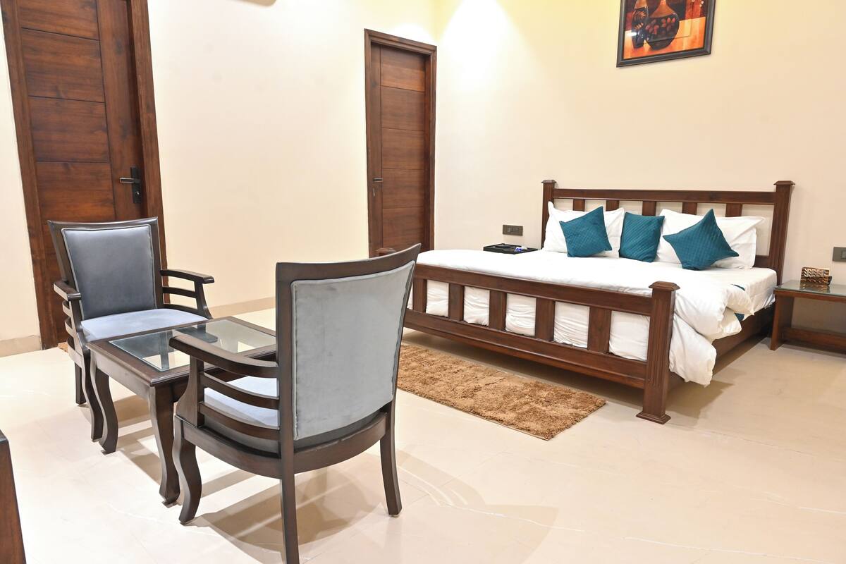 A bedroom with a wooden bed, two chairs, a small table, and a nightstand.