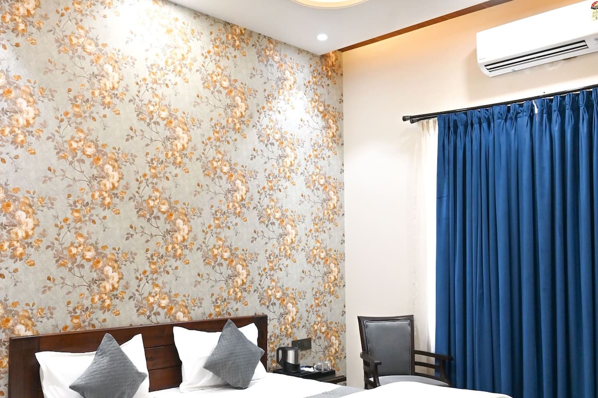 A bedroom with a wooden bed, a nightstand, a bedside table, a ceiling fan, and a window with blue curtains.