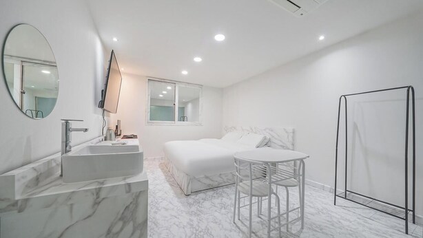 Een moderne badkamer met een marmeren wastafel, een grote spiegel, een bed en een douche.