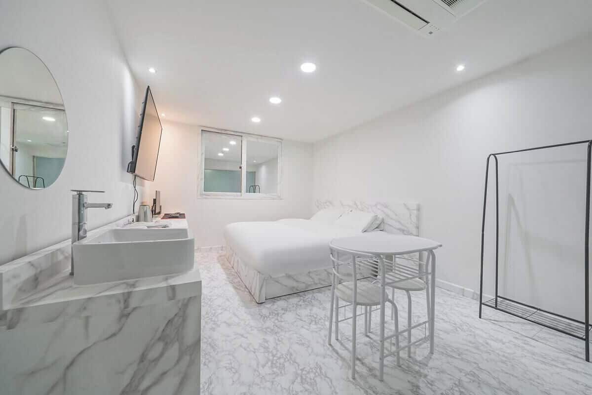 Een moderne badkamer met een marmeren wastafel, een grote spiegel, een bed en een douche.