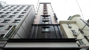 Een hoog gebouw met een modern architectonisch ontwerp, met een opvallende ingang met zuilen en een grote glazen gevel.