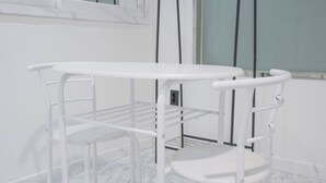 Een witte metalen tafel met planken en een stoel in een kamer met marmeren vloer en witte muren.