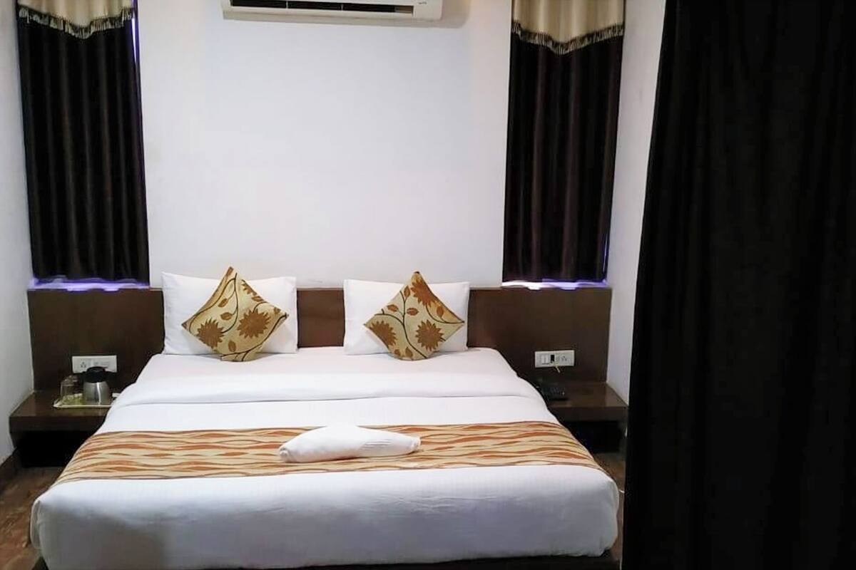 A hotel room with a large bed, two nightstands, and a window with curtains.
