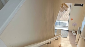 Eine Teppichstiege mit Handlauf, eine Tür mit Fußmatte und eine Wand mit einer Blumenaufkleber.