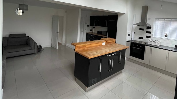 Eine moderne Küche mit Oberlichter, schwarzen Schränken und einer Holz Arbeitsplatte.