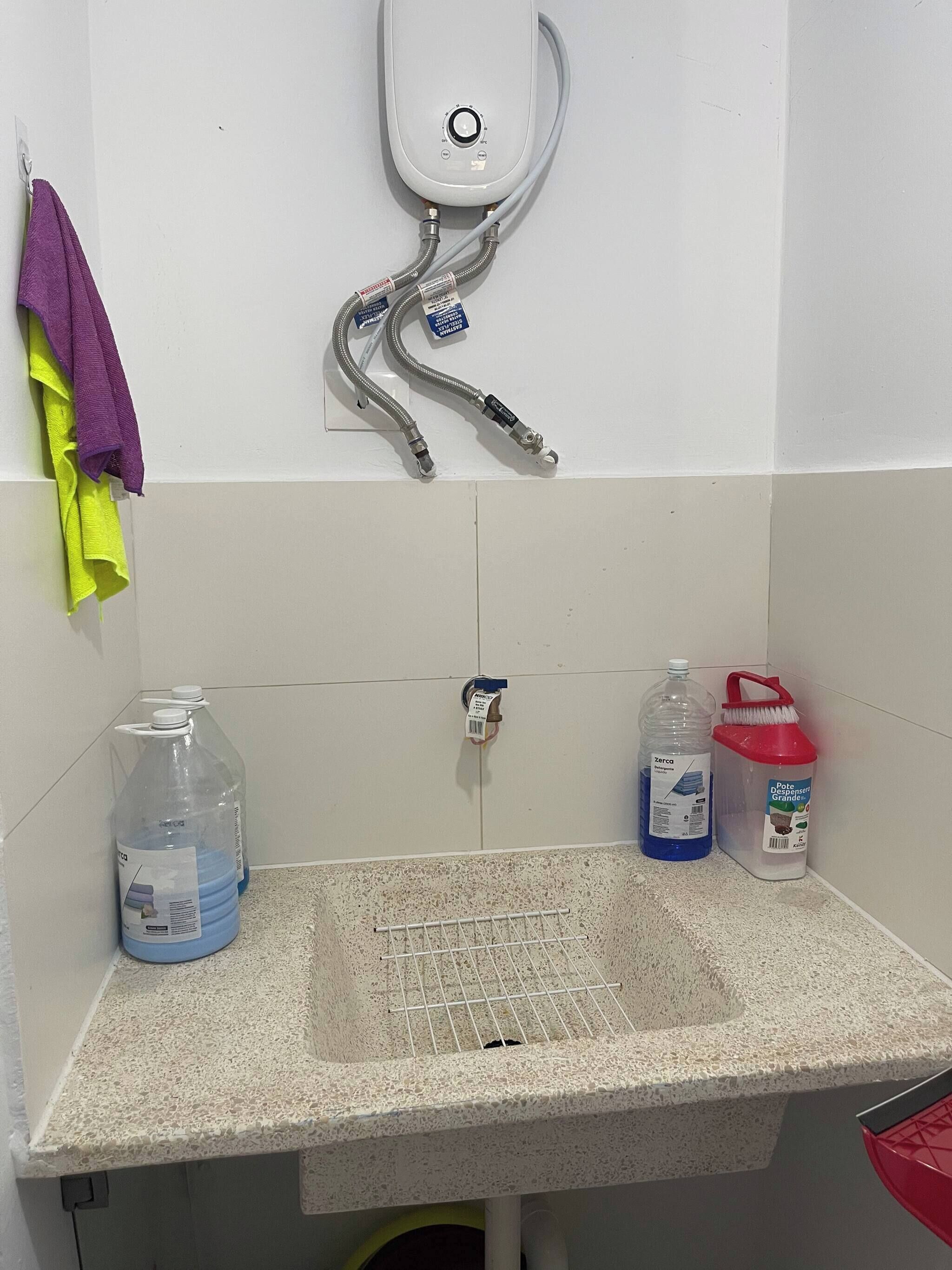 A bathroom with a sink, a hand dryer, and cleaning supplies.