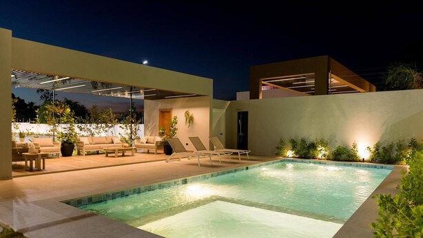 A modern outdoor pool area with lounge chairs and a covered seating area. - Mountain and Pool Modern Apartment (Santiago de los Caballeros)