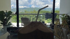 A room with a large window offering a view of green hills and a clear sky. - Mountain and Pool Modern Apartment (Santiago de los Caballeros)