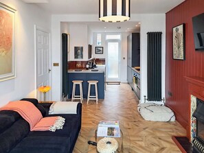 A modern living room with a dark sofa, a glass coffee table, and a fireplace. - 2 bedroom accommodation in Shotley Gate (Shotley Gate)