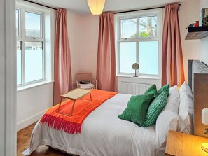 A bedroom with a bed, a bedside table, a chair, and a window with curtains. - 2 bedroom accommodation in Shotley Gate (Shotley Gate)