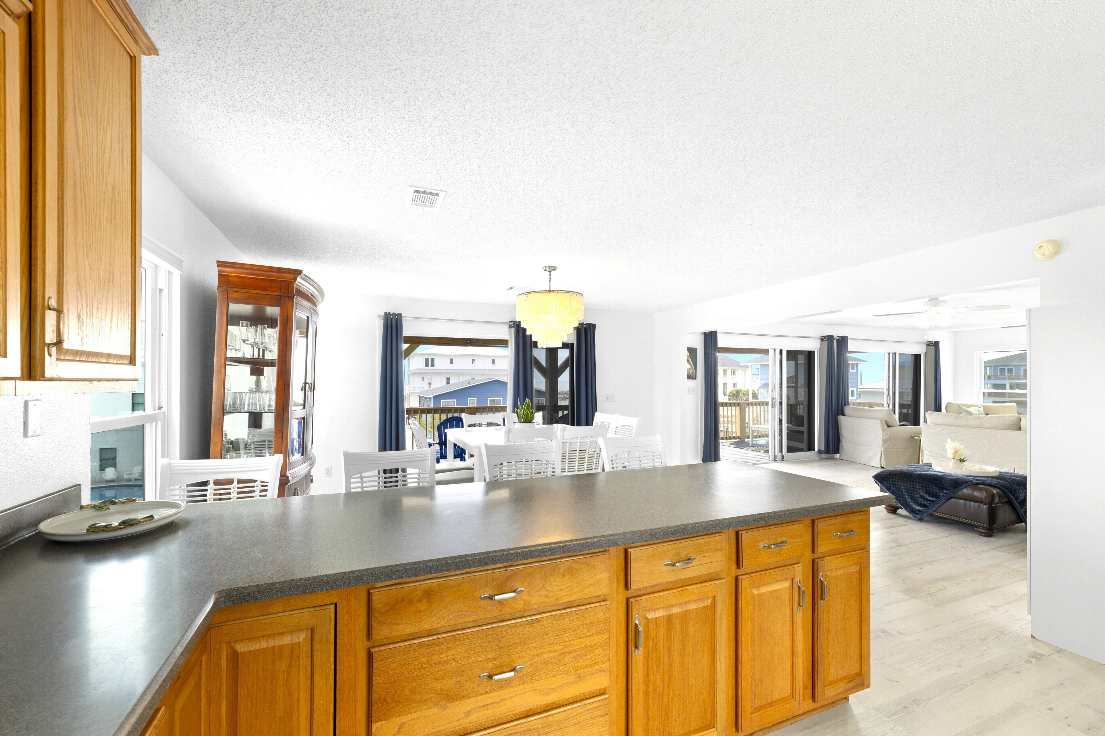 A modern kitchen with wooden cabinets, a granite countertop, and a dining area with white furniture.