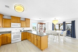A kitchen with wooden cabinets, a white stove, and a large island with a sink. - Sea Shell Villa Pensacola Beach Home w/ Amazing Gulf Views (pensacola beach)