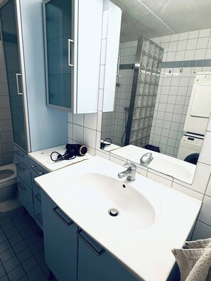 Et moderne badeværelse med en hvid vask, et spejl og et toilet.